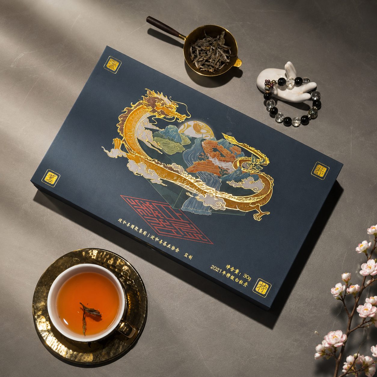龙纹礼盒俯拍,旁置茶则与一杯橙黄茶汤